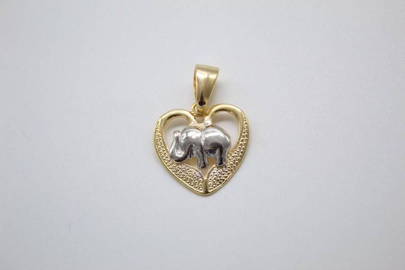 A gold and silver heart-shaped pendant featuring a textured elephant design rests against a plain white background.