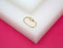 A shiny gold screw-lock carabiner charm rests on a white block against a bright pink background.