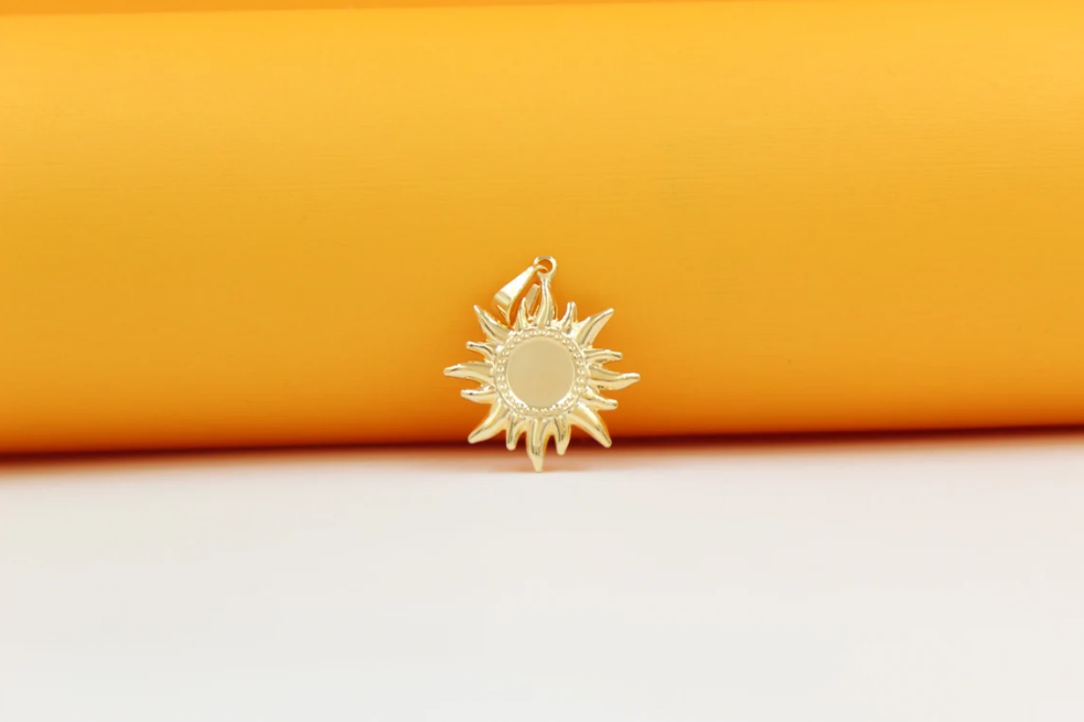 A gold sunburst pendant rests against a bright yellow and white background.