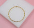 A delicate gold chain bracelet rests centered on a white display pad against a soft pink background.