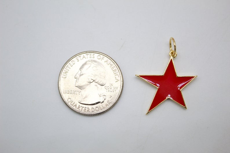 A shiny red enamel star charm sits next to a US quarter coin to show its scale.