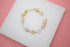 A delicate gold tri-color butterfly bracelet rests on a white display surface against a pink background.