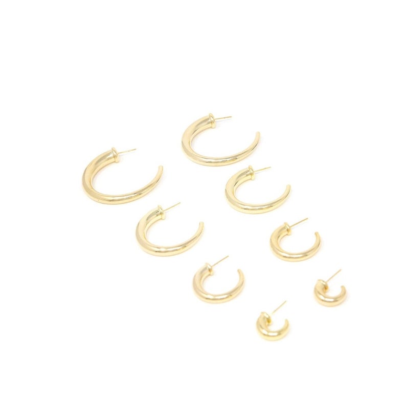 A collection of shiny gold hoop earrings in descending sizes is arranged neatly on a white surface.