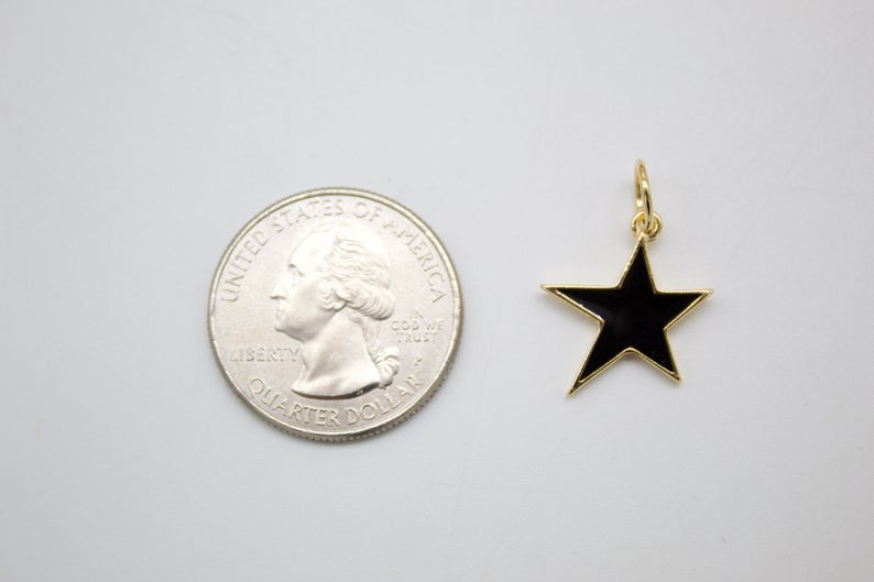 A gold-rimmed black enamel star charm rests beside a US quarter coin for scale.