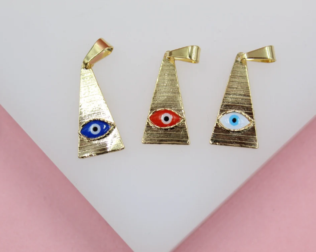 Three gold triangular evil eye pendants in blue, red, and white rest on a white surface.