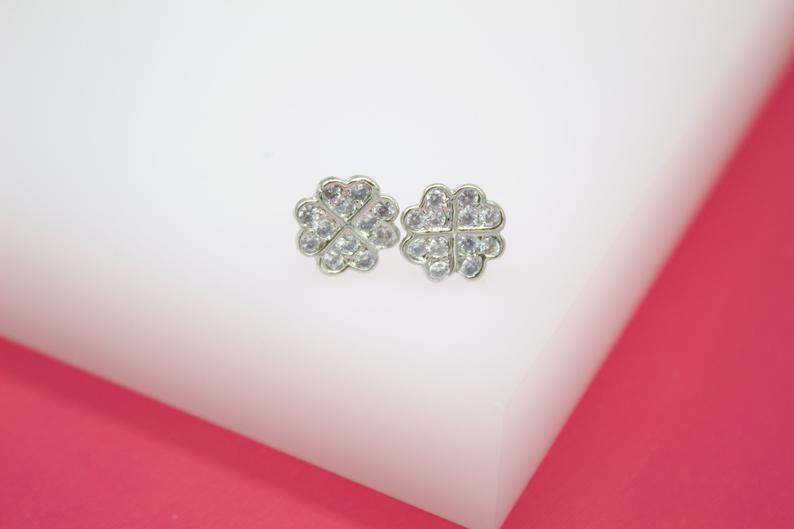 Sparkling silver four-leaf clover stud earrings rest on a clean white surface.