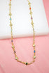 A gold chain necklace features alternating gold hearts and colorful gemstones against a pink and white background.