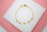 A delicate gold chain bracelet features colorful, crystal-embellished four-leaf clover charms displayed on a white surface.