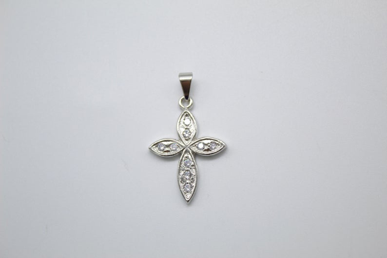 A silver cross pendant adorned with sparkling cubic zirconia stones rests against a light gray background.