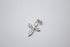 A delicate silver cross pendant embellished with sparkling cubic zirconia stones lies on a plain white surface.
