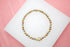 A tri-color beaded stretch bracelet featuring alternating yellow gold, rose gold, and silver spheres rests on a white display surface.