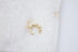 A gold beaded ear cuff rests on a white marble surface.