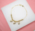 A delicate gold-plated chain bracelet features a row of shiny spherical beads and three dangling elephant charms on a white display surface.