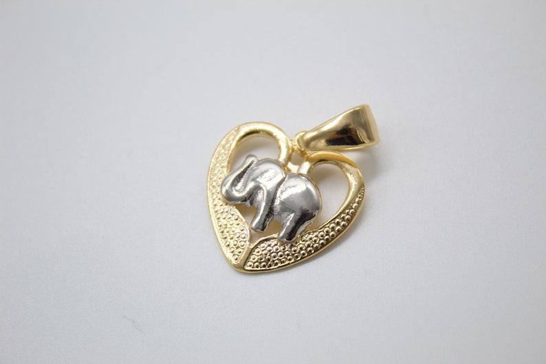 A two-tone gold pendant features a silver elephant standing inside a textured gold heart frame.