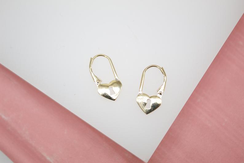 A pair of shiny gold leverback earrings features heart-shaped pendants with delicate keyhole cutouts.