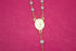 A delicate gold rosary necklace with white pearl beads and a central religious medallion rests against a vibrant pink background.