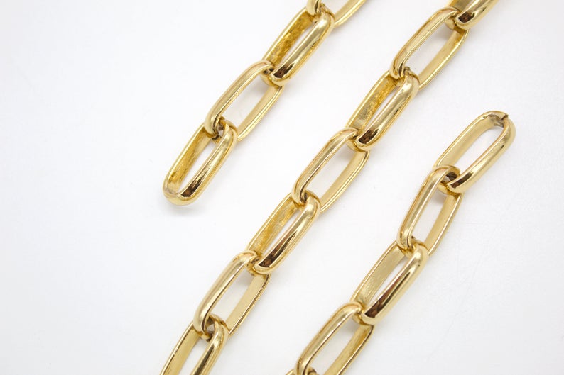 A polished gold paperclip chain necklace rests against a clean white background.
