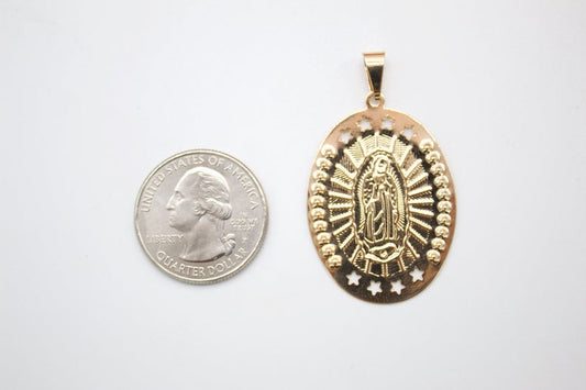 An oval gold Our Lady of Guadalupe pendant rests beside a US quarter for size comparison.