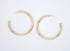A pair of thick gold hoop earrings rests side-by-side against a plain white background.