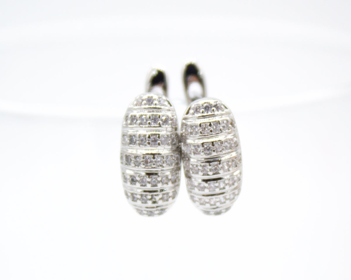 A pair of silver hoop earrings studded with shimmering cubic zirconia stones rest against a clean white background.