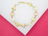 A delicate tri-color gold butterfly link bracelet rests on a white and pink display surface.