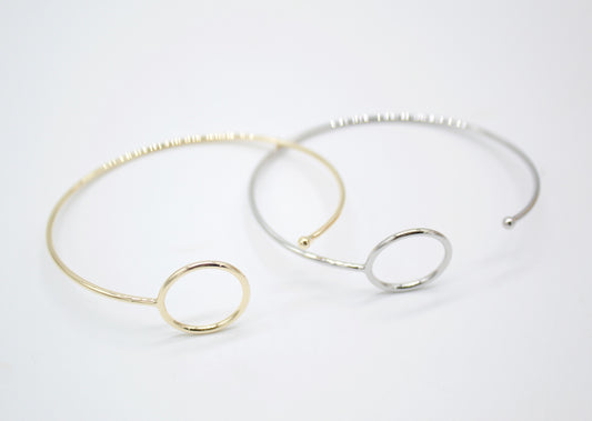 Two elegant gold and silver bangle bracelets feature interlocking circular charms on a clean white background.