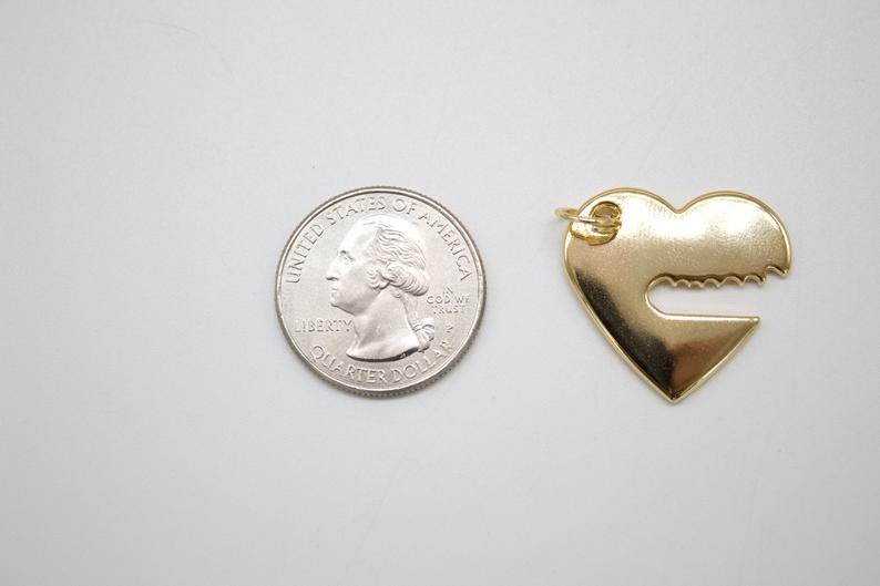 A US quarter coin sits next to a gold-plated heart pendant for size comparison on a white surface.