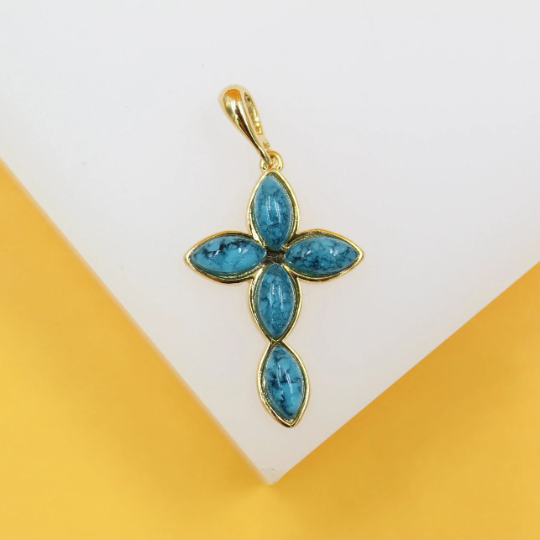 A gold cross pendant features five marquise-cut turquoise stones against a white and yellow background.