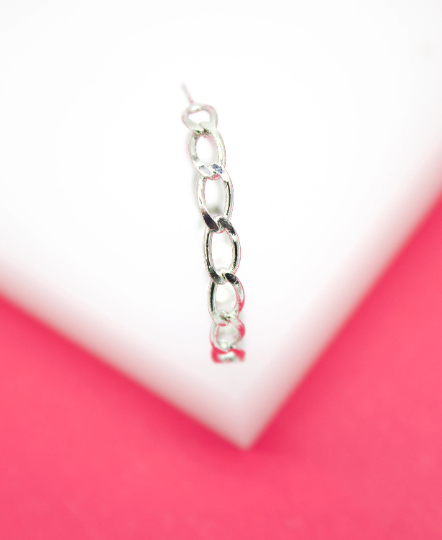 A silver chain link hoop earring rests against a white and pink background.
