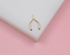 A small gold wishbone charm rests on a white and pink surface.