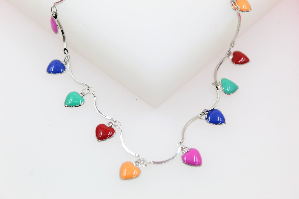 A silver charm bracelet features colorful enamel heart charms in shades of red, blue, green, pink, and orange.