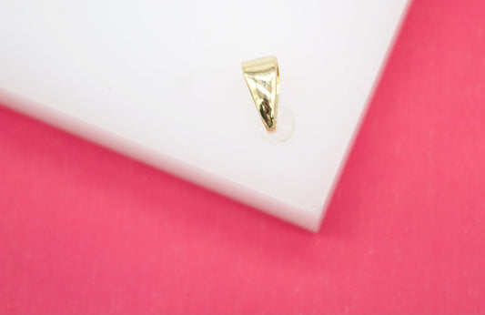 A polished gold bail rests on a white display surface against a vibrant pink background.