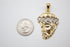 A two-tone gold Jesus head pendant rests next to a US quarter coin to show its scale.