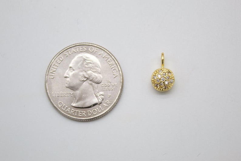 A tiny gold pave-set CZ circle charm sits next to a US quarter for size comparison.