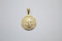 A polished gold Saint Benedict medal pendant displays intricate religious engravings against a neutral background.