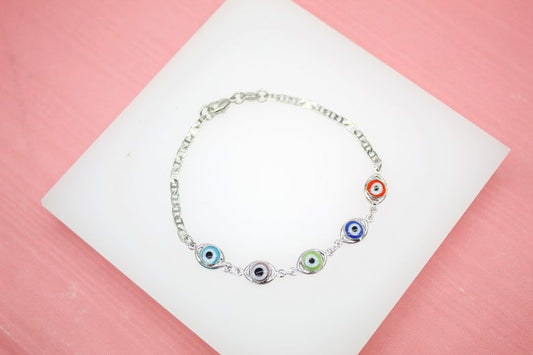 A delicate silver chain bracelet features colorful evil eye charms in shades of light blue, dark blue, green, and red against a soft pink background.