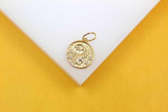 A round gold pendant features an embossed star sign design embellished with tiny sparkling stones.