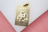 A rectangular gold pendant features a textured engraving of the Virgin Mary holding baby Jesus with a small crystal accent.