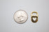 A small gold soda tab charm with a black enamel heart cutout sits next to a US quarter coin for scale.