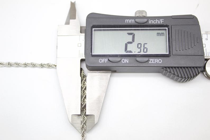 A digital caliper measures the thickness of a silver rope chain at 2.96 mm.