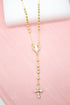 A delicate gold rosary necklace featuring bead spacers, a rhinestone-encrusted centerpiece, and a sparkling cross pendant rests on a pink surface.