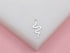 A sleek silver snake stud earring rests on a white display surface against a soft pink background.