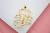 A textured gold scorpion pendant rests on a clean white surface.