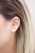 A woman wears a unique gold bar earring with decorative beads spanning across her earlobe and conch.