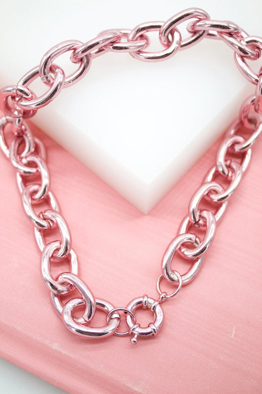A shiny metallic pink chain necklace rests on a pink and white background.