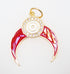 A gold-plated charm features a vibrant red enamel crescent shape accented by a sparkling rhinestone halo and a central white evil eye symbol.