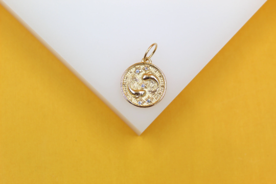 A gold Pisces zodiac charm necklace pendant displays the two fish symbols embellished with sparkling cubic zirconia stones.