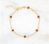 A delicate gold chain bracelet features sparkling brown sunstone beads laid out against a white marble background.