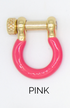 A U-shaped gold hardware shackle features a vibrant pink enamel lower half and a textured screw pin closure, labeled PINK at the bottom.