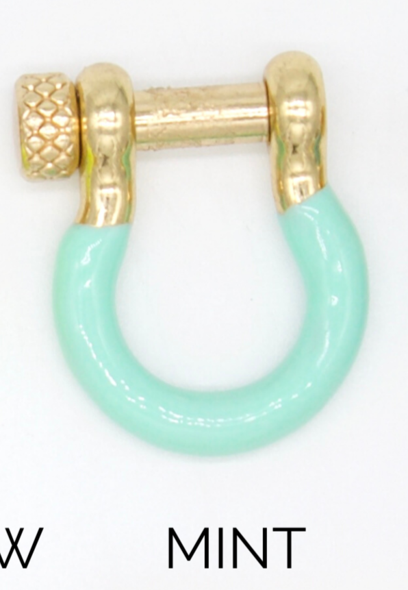 A mint green enamel and gold horseshoe-shaped shackle earring rests against a white background.